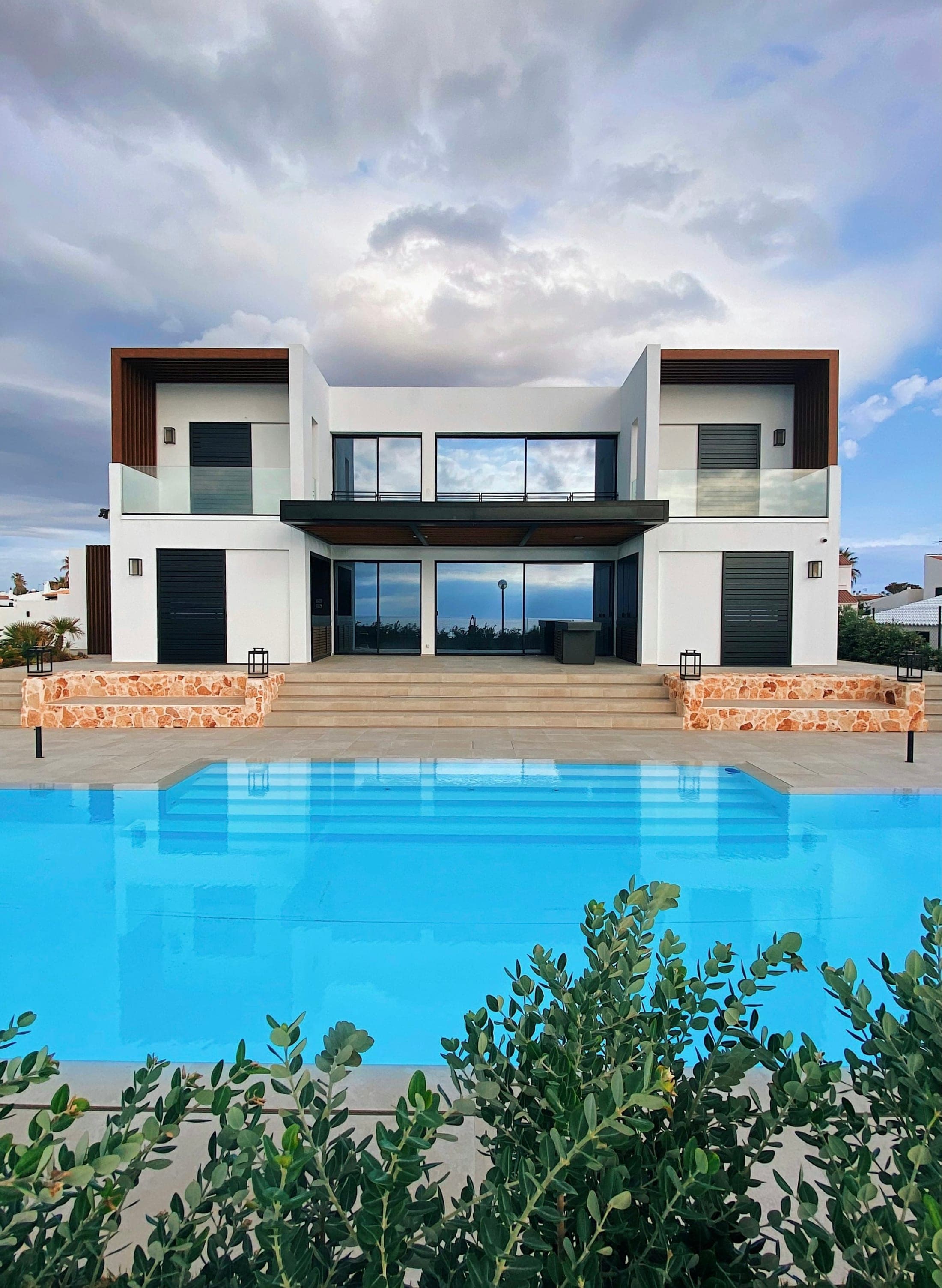 Modern luxury home with pool under a dramatic sky